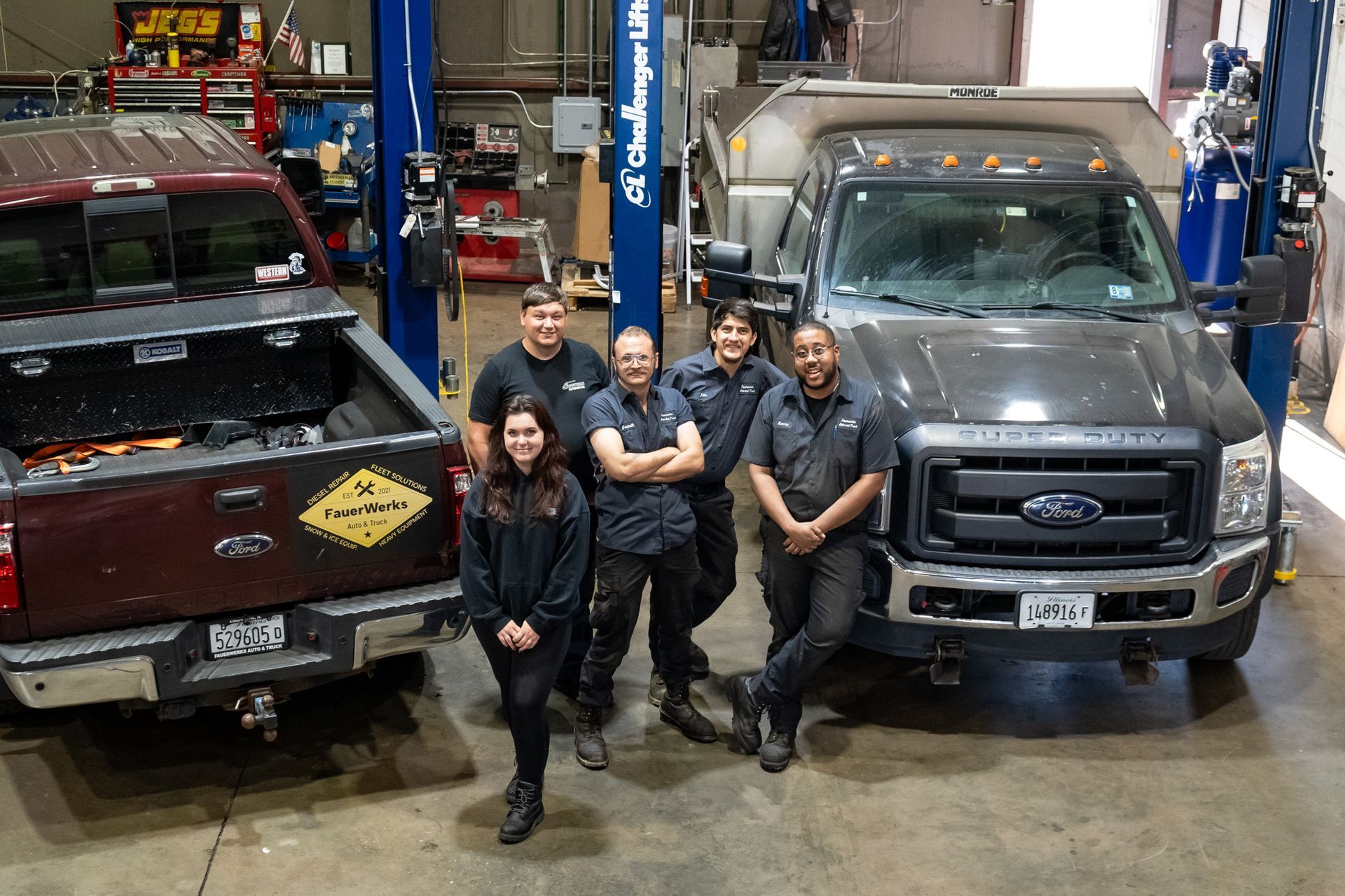 Team Members Standing in a Garage with Two Pickup Trucks | FauerWerks Auto & Truck