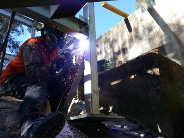 a Man is Grinding a Piece of Metal With a Grinder in a Factory — Real Engineering In West Gosford, NSW