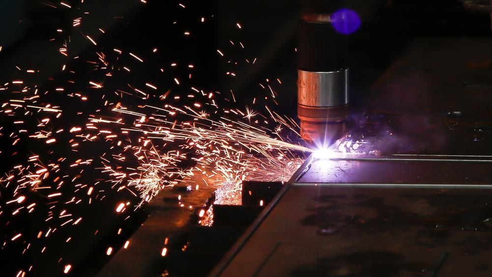 a Machine is Cutting a Piece of Metal With Sparks Coming Out of It — Real Engineering In West Gosford, NSW