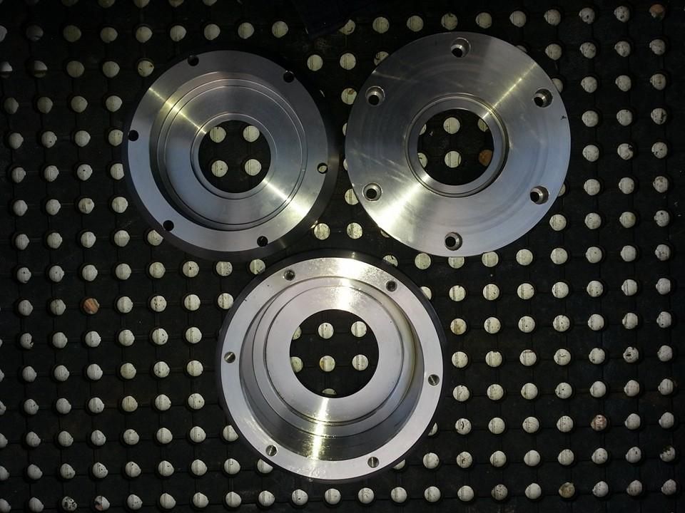 Three Metal Circles With Holes in Them Are Sitting on a Black Mat — Real Engineering In West Gosford, NSW