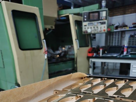 Factory machinery and metal parts on a workbench in an industrial workshop — Real Engineering In Gosford, NSW