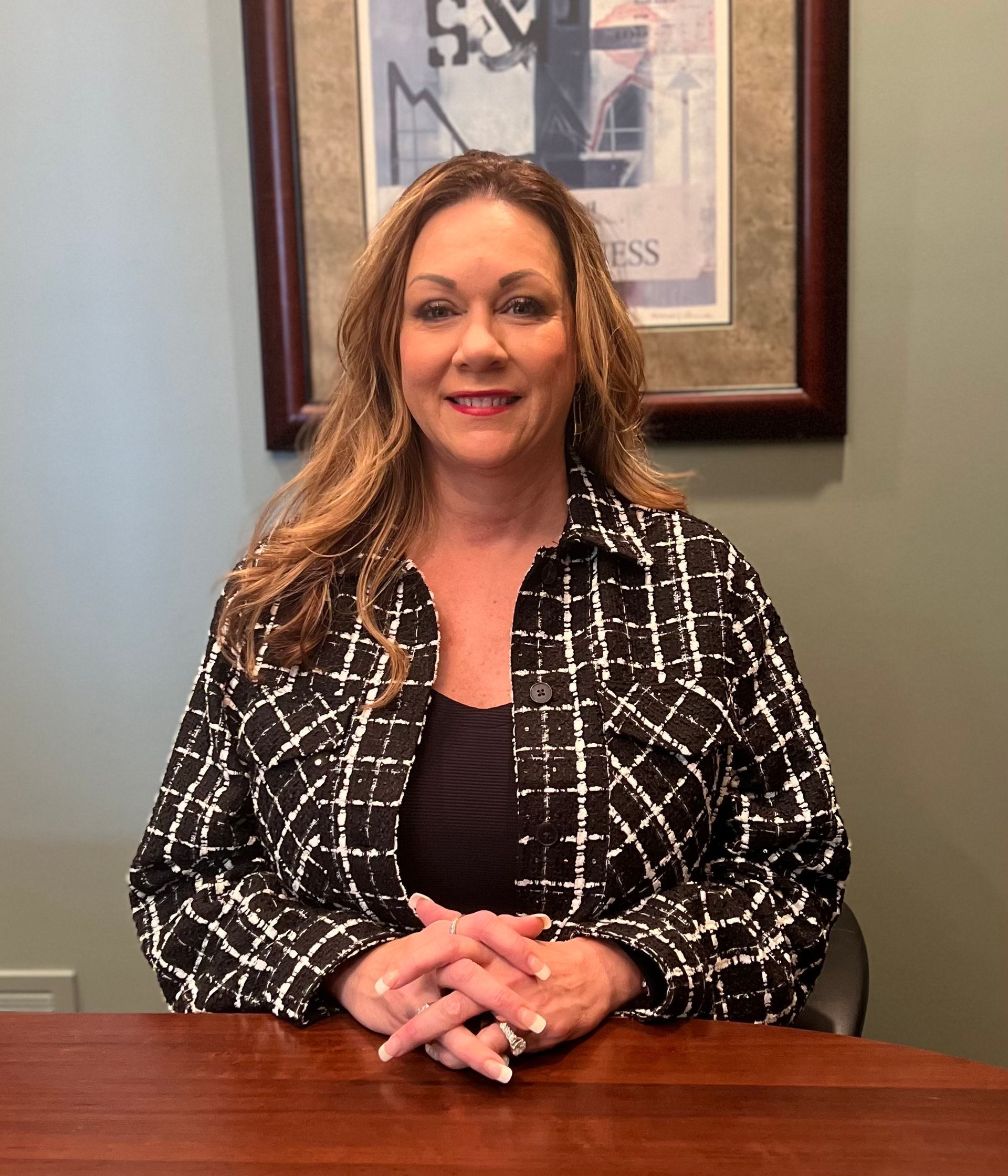 A woman is sitting at a table with her hands folded