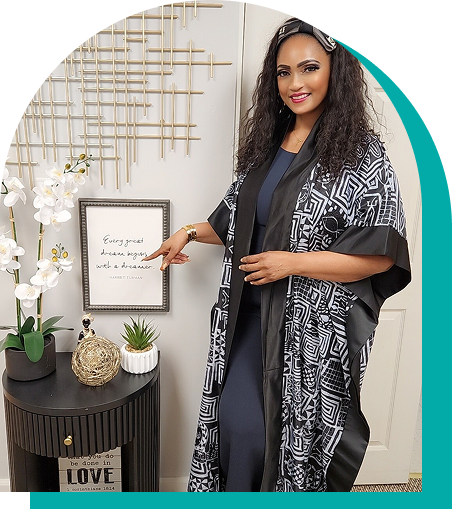 Woman wearing patterned robe points to framed quote next to decor on a table.
