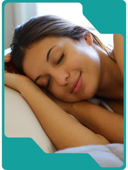 Woman asleep, smiling, resting head on pillow.