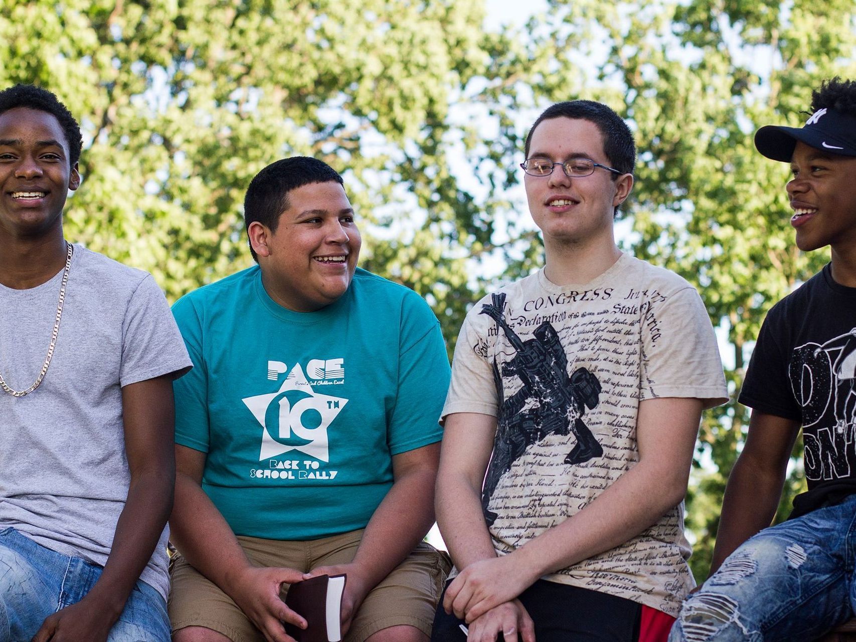 A group of young men are sitting next to each other with one wearing a shirt that says page 19