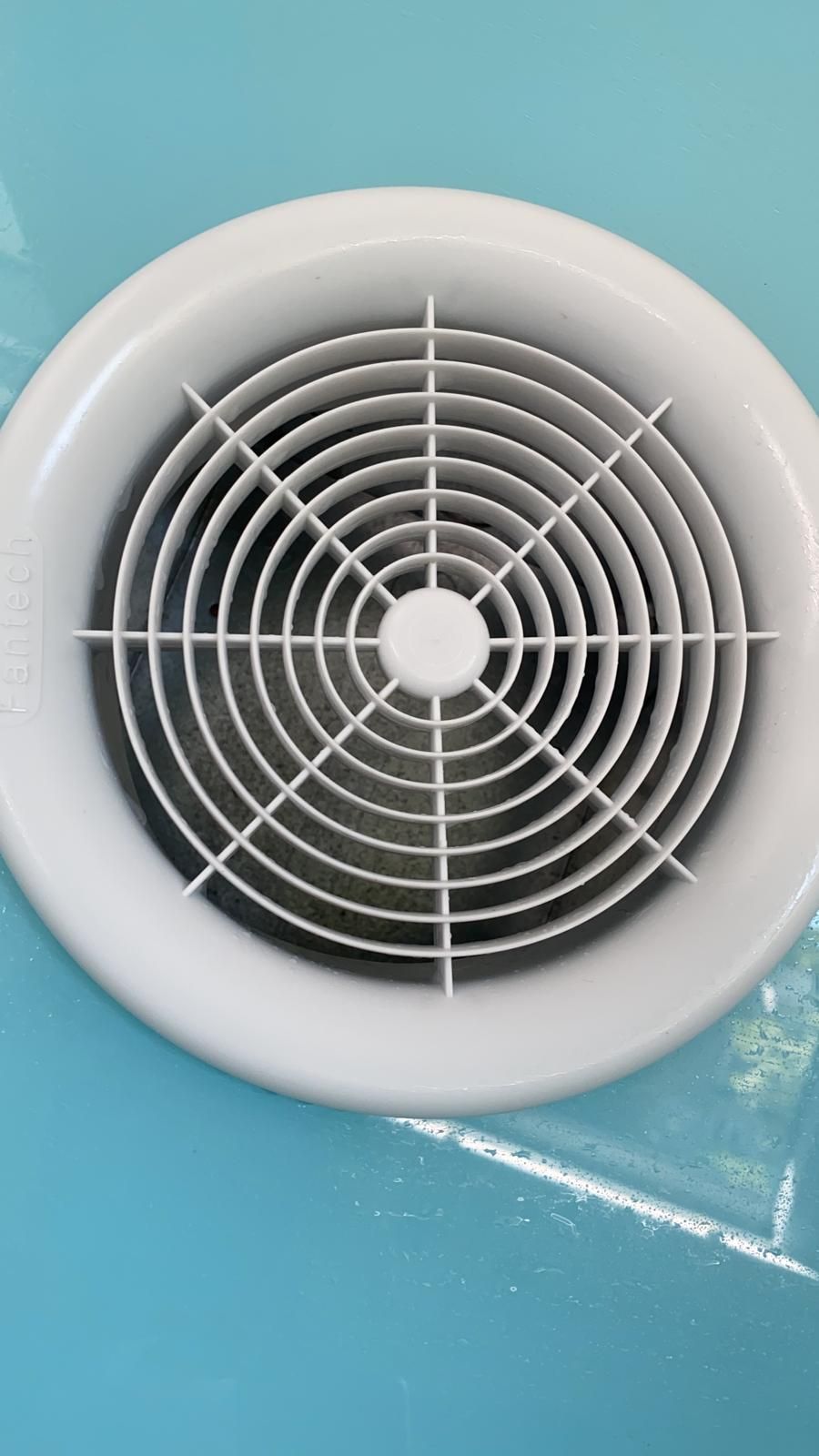 White circular air vent on a blue surface, with concentric grill design.