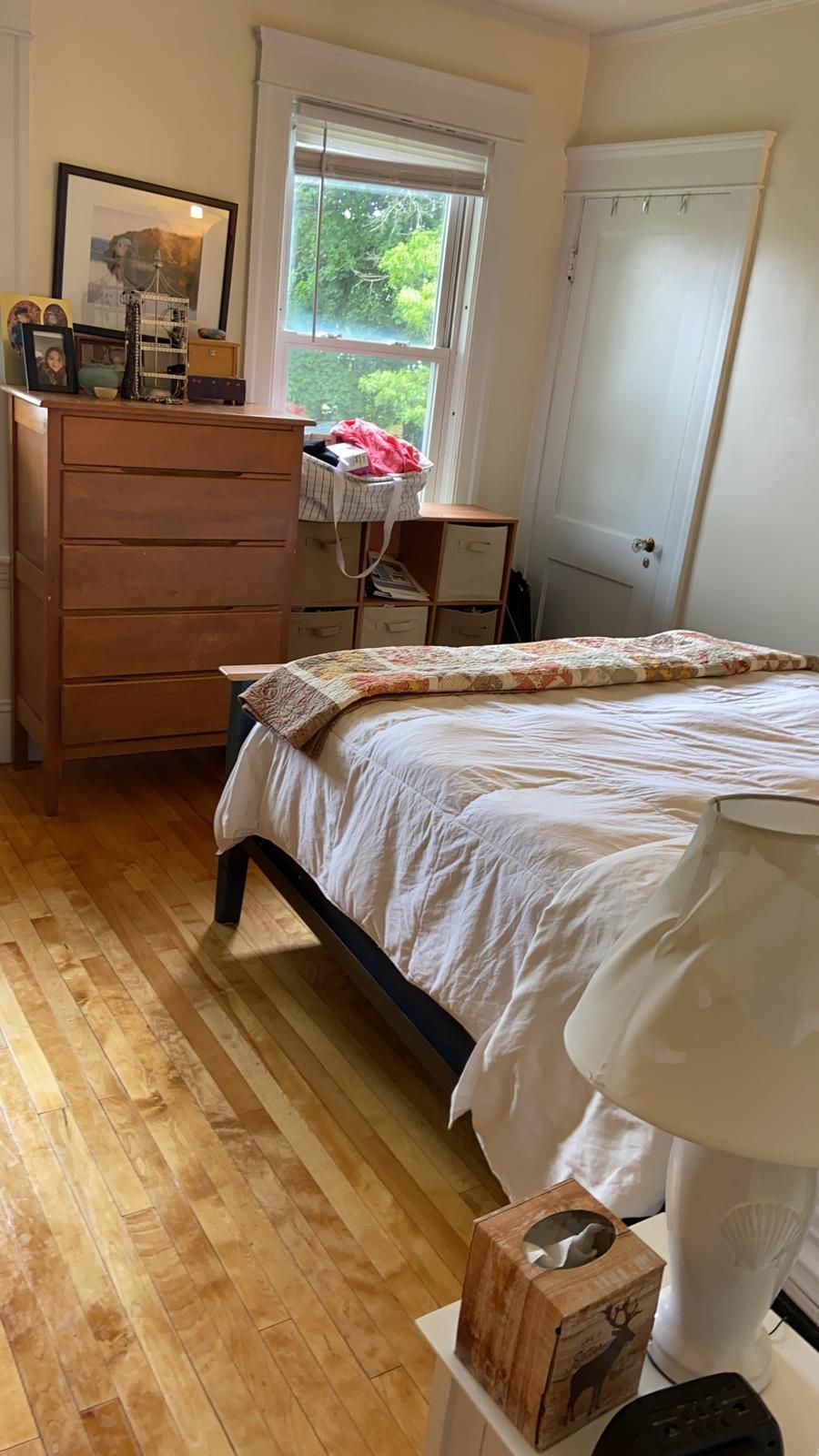 Bedroom with hardwood floors, bed, dresser, window, and door.