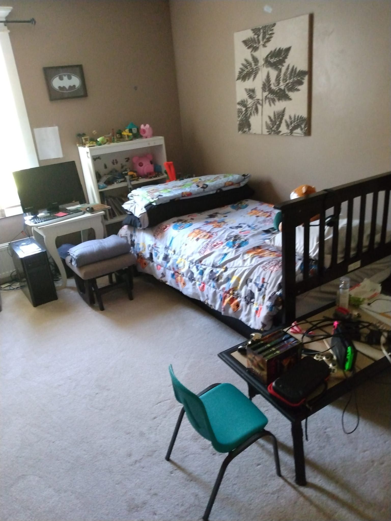 Bedroom with bed, desk, chair, and decorative items.