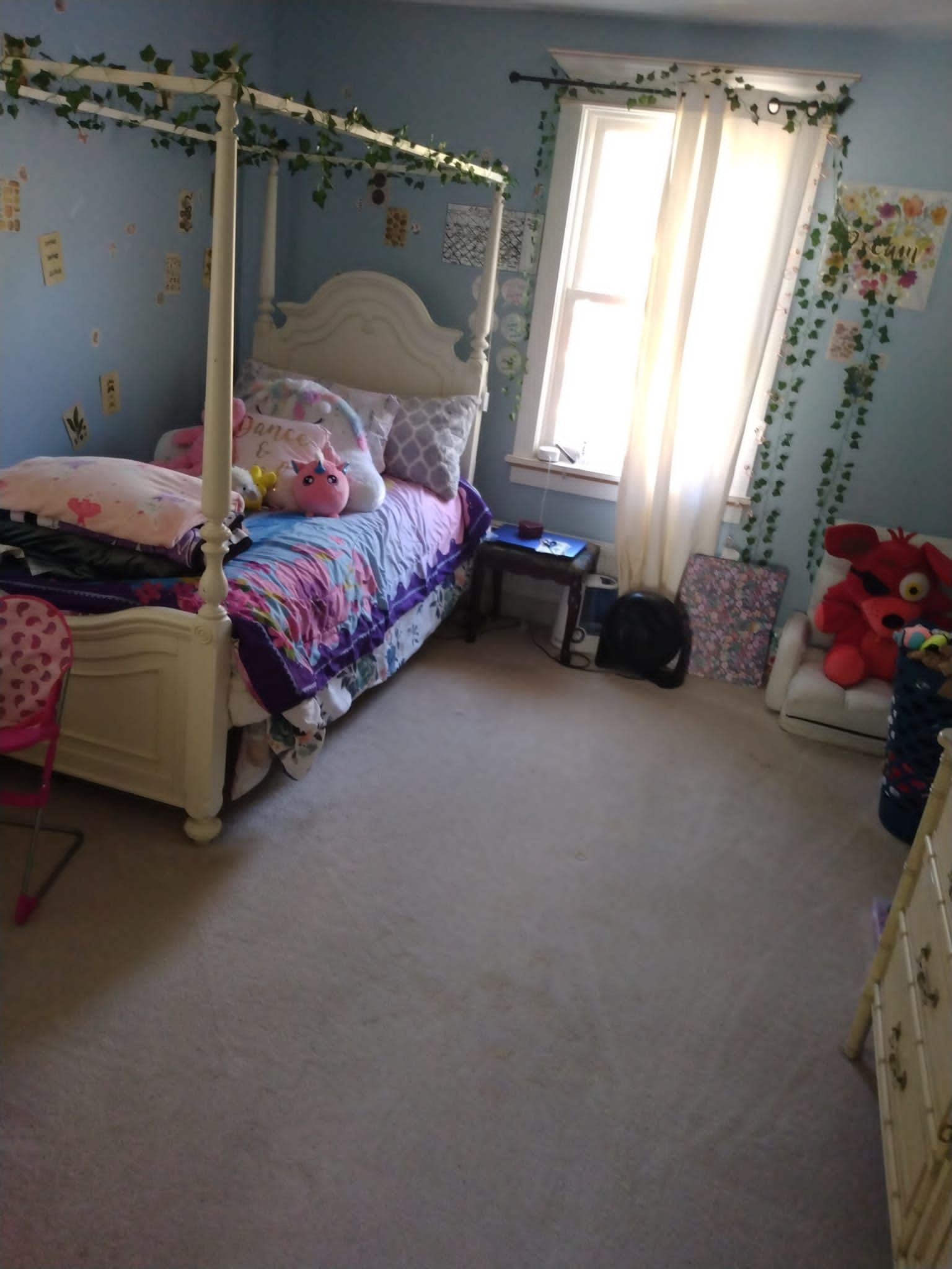 Bedroom with a four-poster bed, window, and light blue walls. Green vines decorate the walls and bed frame.