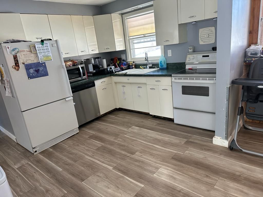 Kitchen with white cabinets, stainless steel appliances, and wood-look flooring.