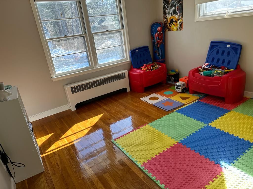 Playroom with two red toy chests, colorful foam floor mats, and a window.