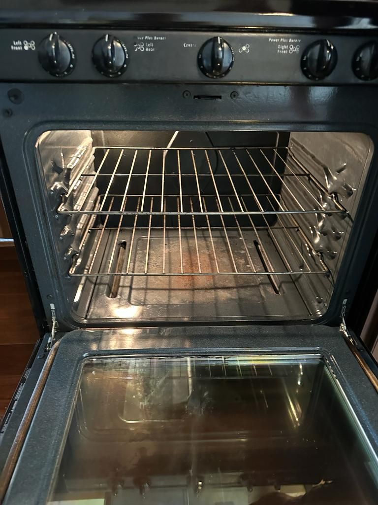 Open black oven with racks inside, dirty bottom.