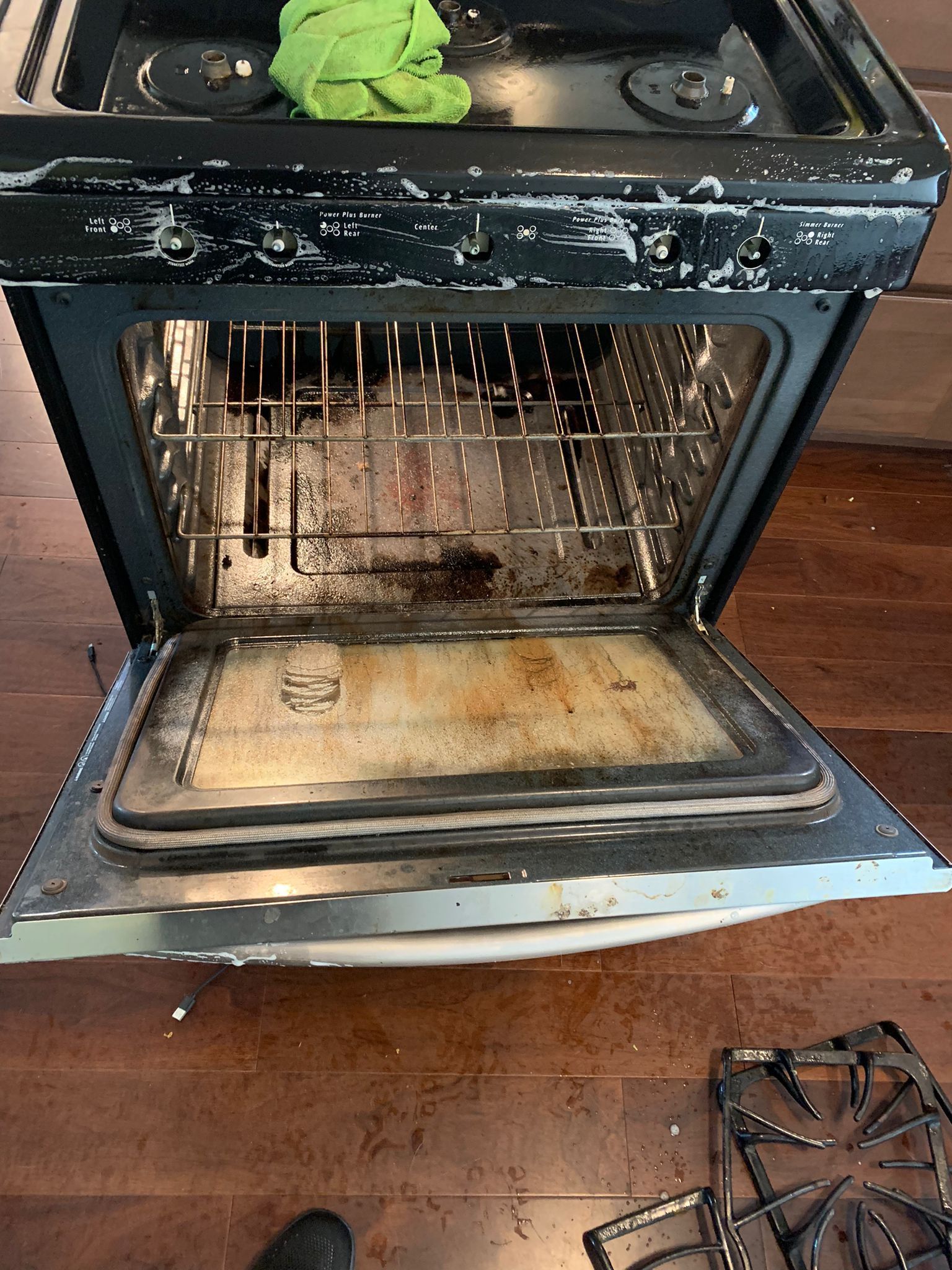Open oven, dirty interior, with a stained bottom and rack, near a stovetop.