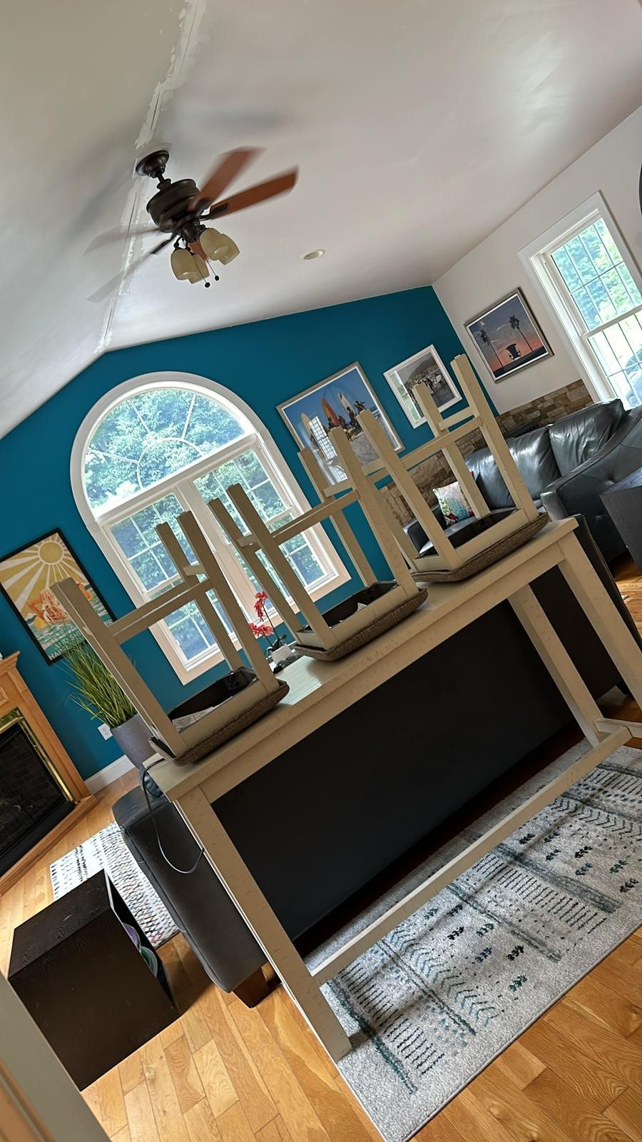 White kitchen island with four matching chairs stacked on top, in a teal room.