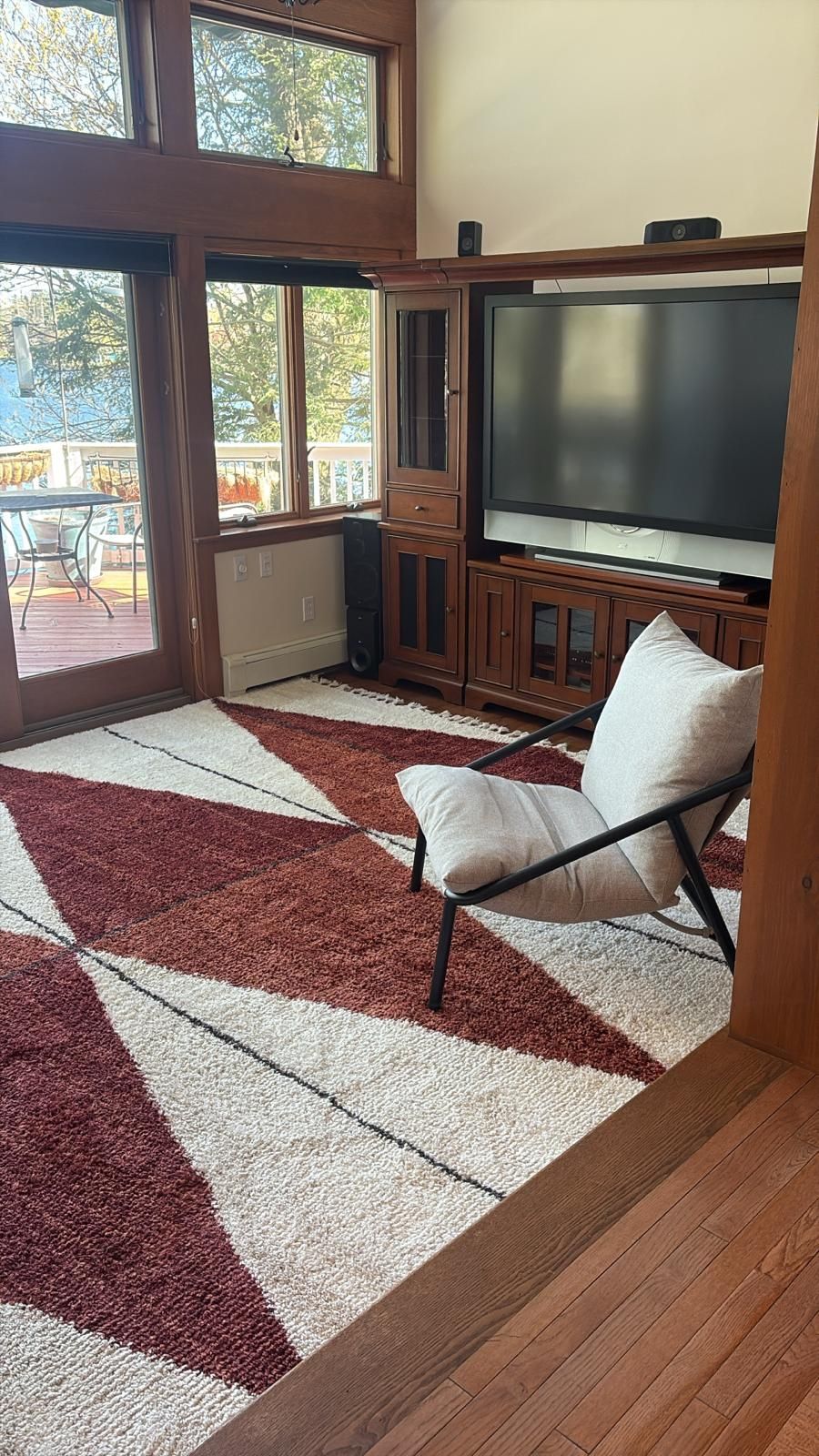 Living room with patterned rug, TV, chair, and large windows.