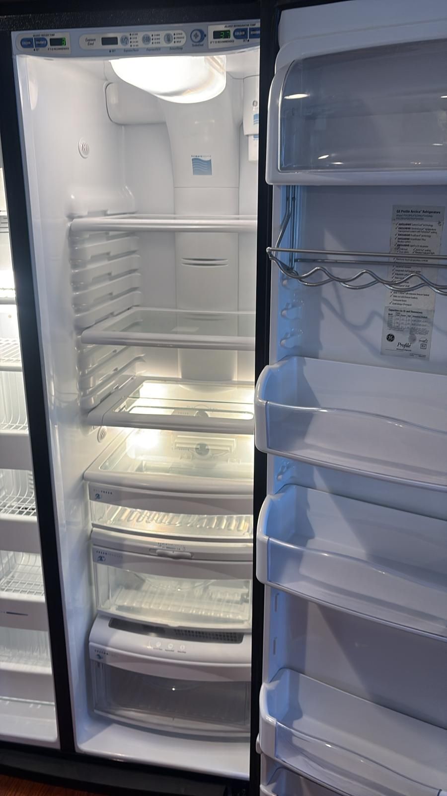 Open, empty, side-by-side refrigerator interior with shelves and drawers.