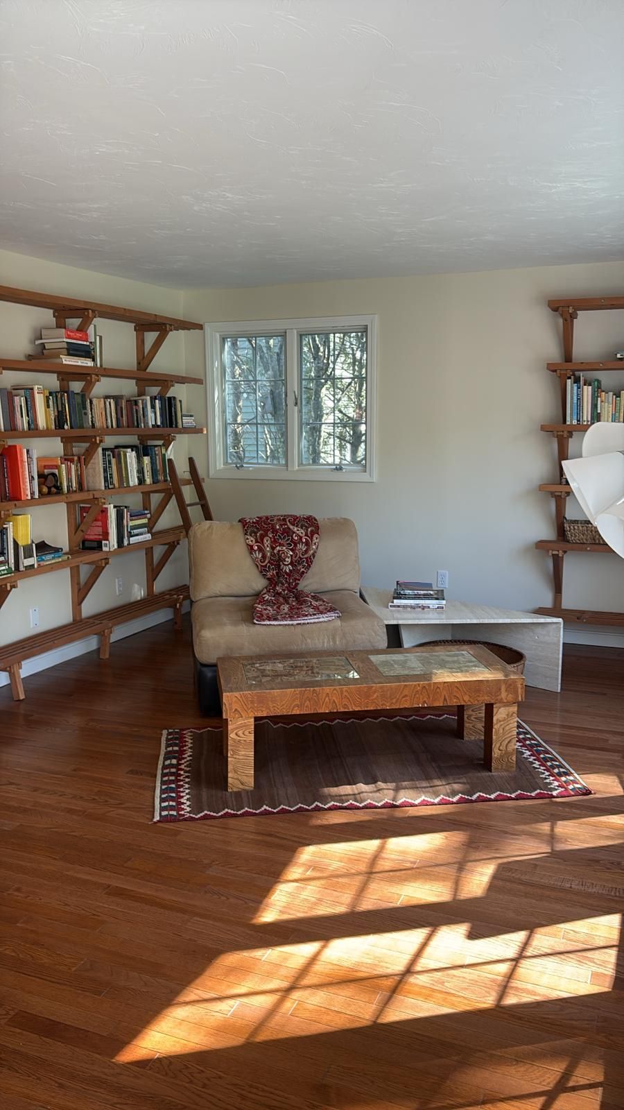 Cozy reading nook with hardwood floors, built-in bookshelves, and a window letting in sunlight.