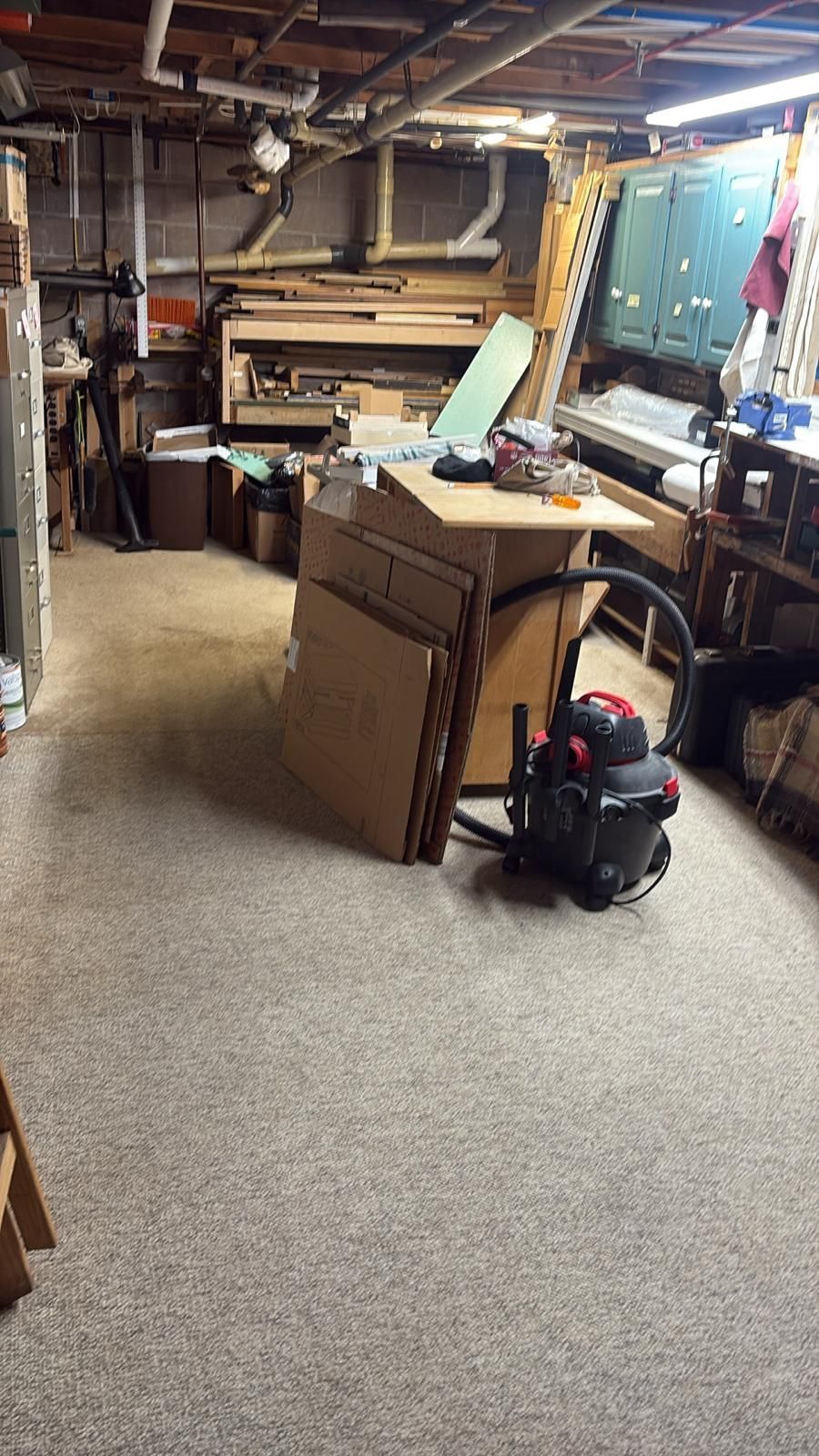 Workshop interior with workbench, vacuum, and stacked cardboard.