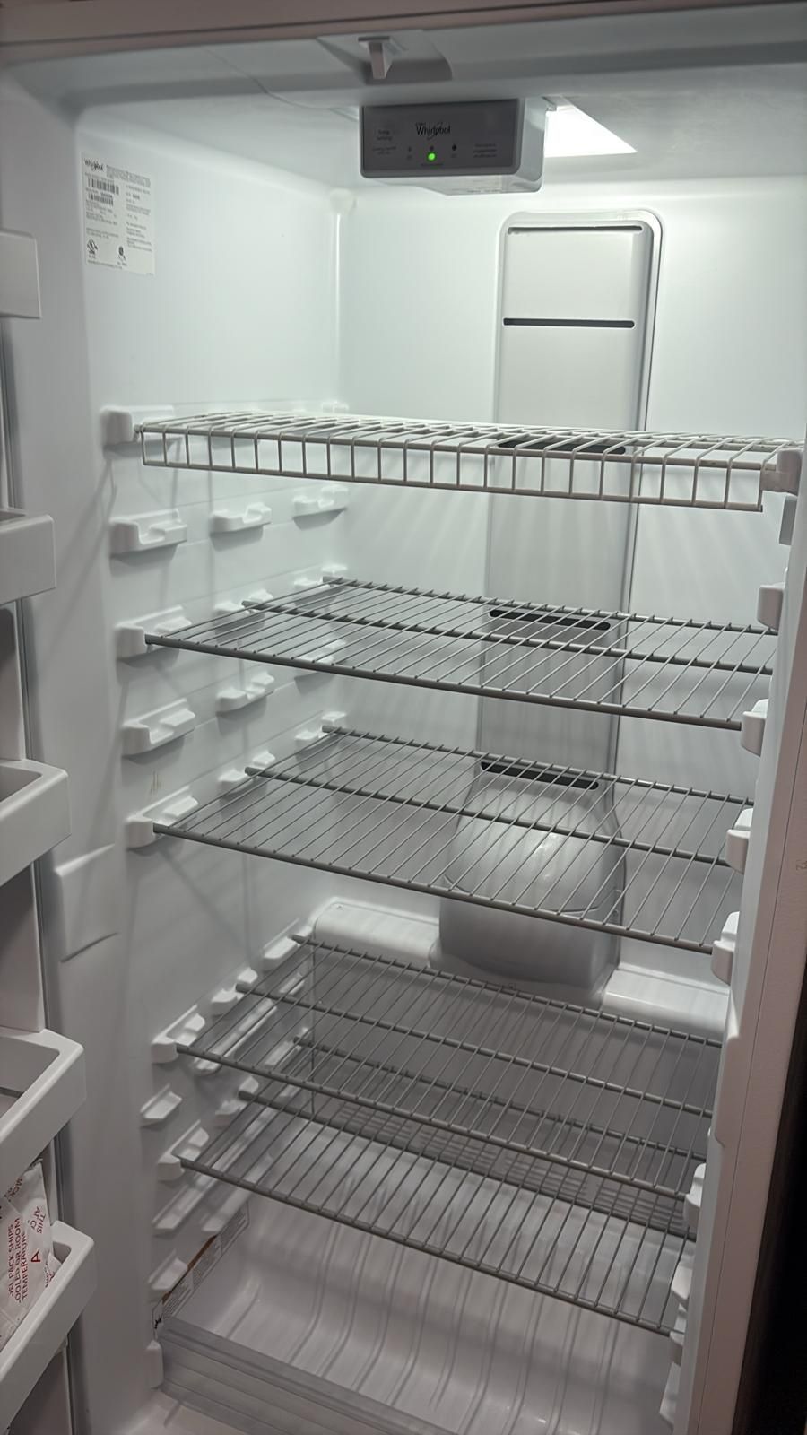 Empty refrigerator interior with wire shelves and a temperature control panel.