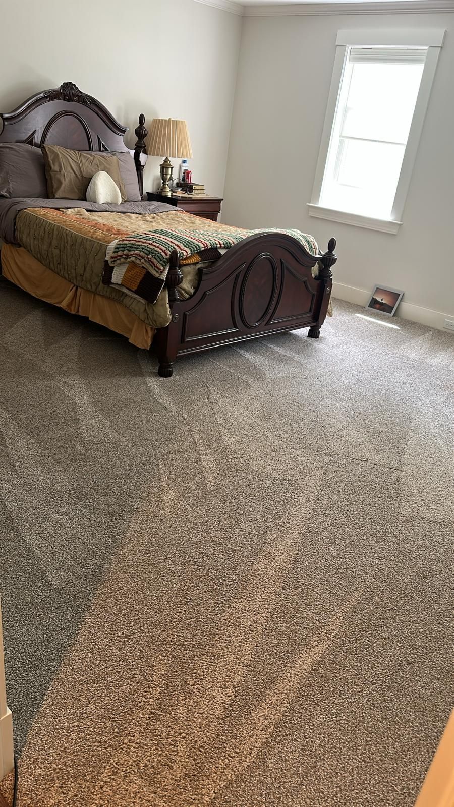 Bedroom with ornate wooden bed, beige carpet, and a window.