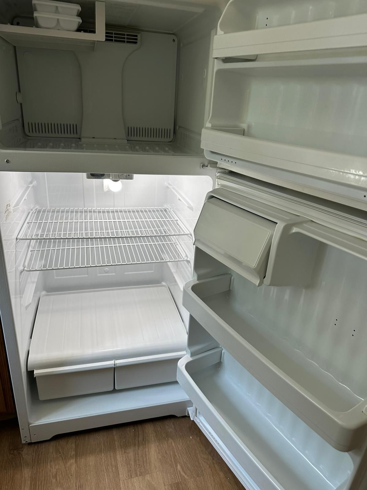 Empty white refrigerator with open doors.