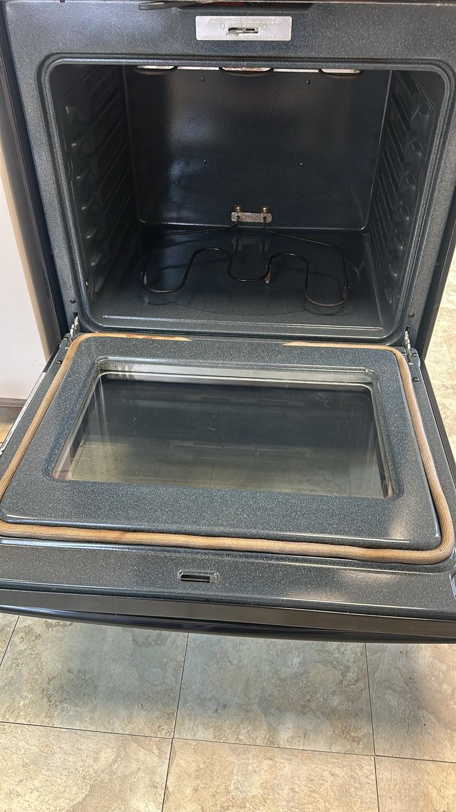 Open oven with a glass door, showing the interior and a brown seal.