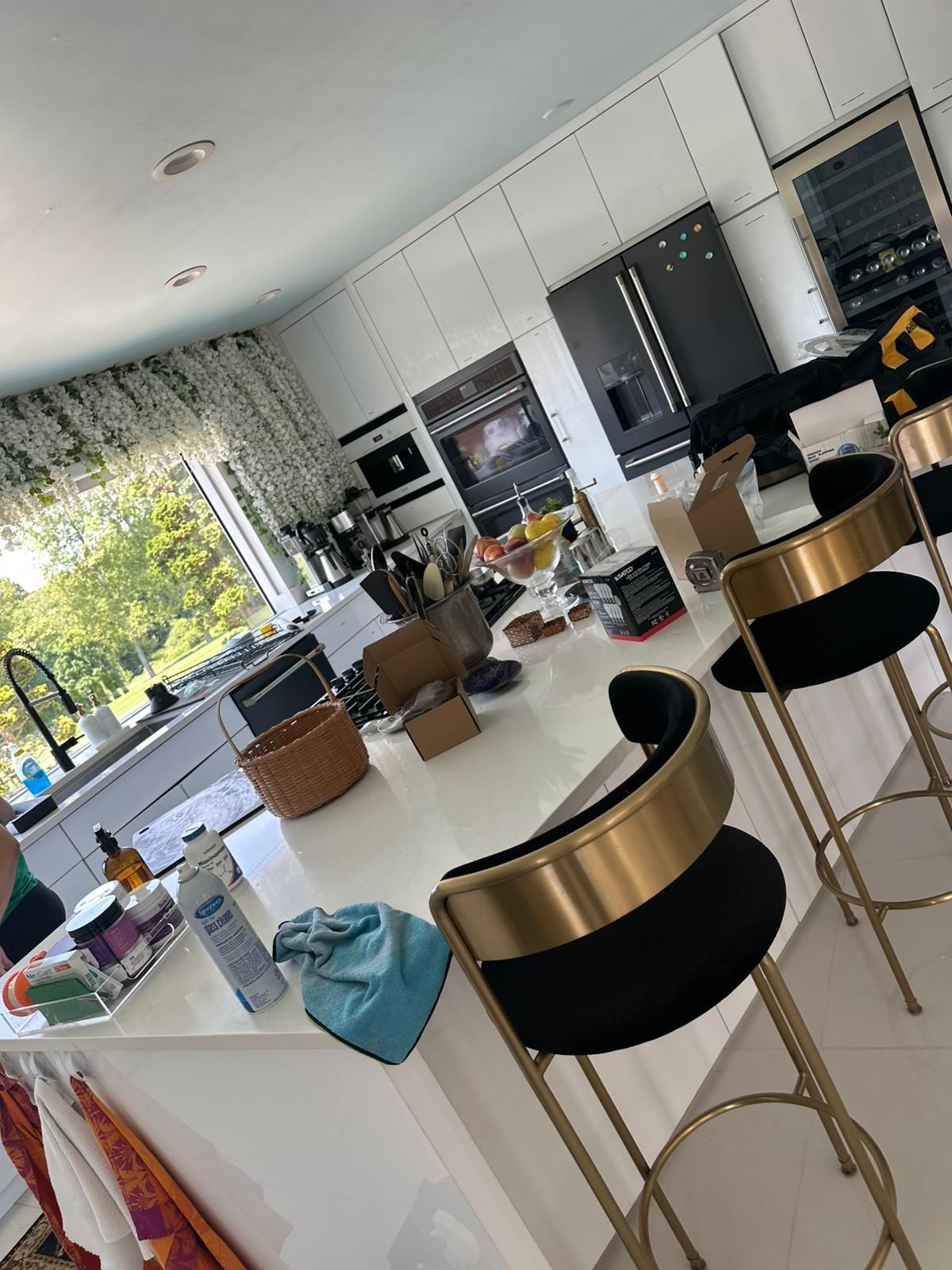 Modern kitchen with white countertops and gold and black bar stools.