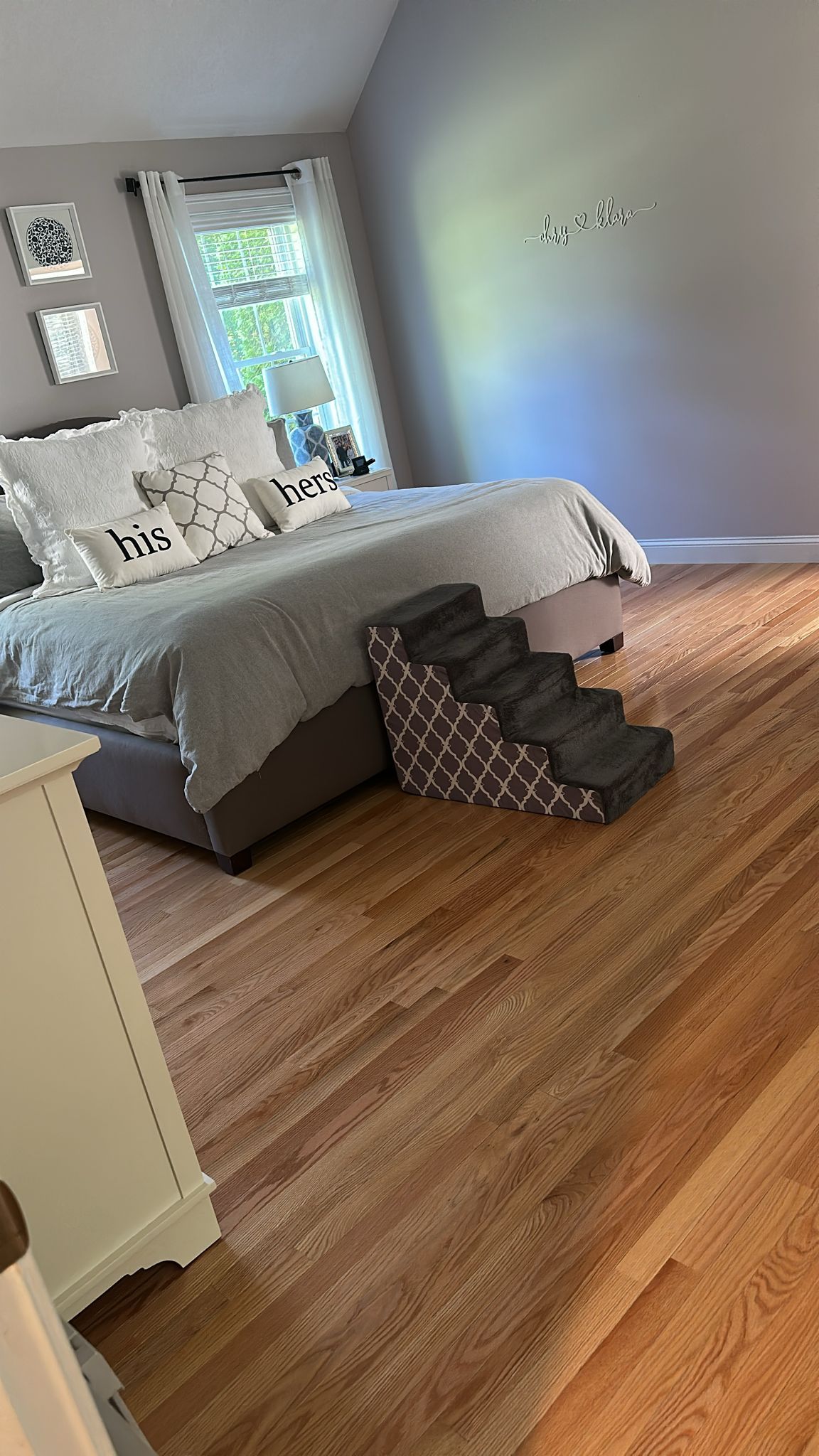 Bedroom with a bed, pet stairs, and hardwood flooring.