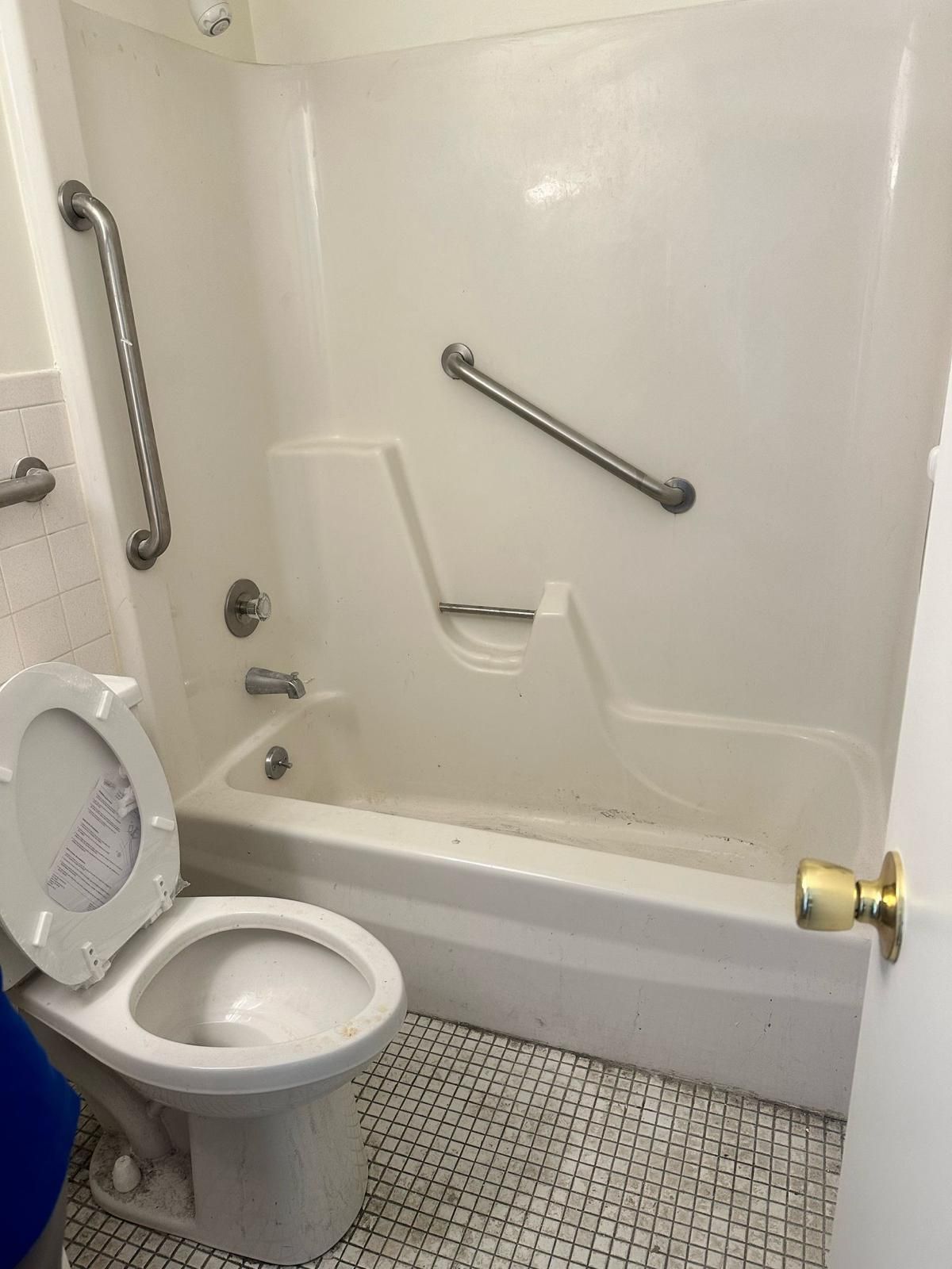 Bathroom with a bathtub, toilet, and grab bars; white and silver fixtures.