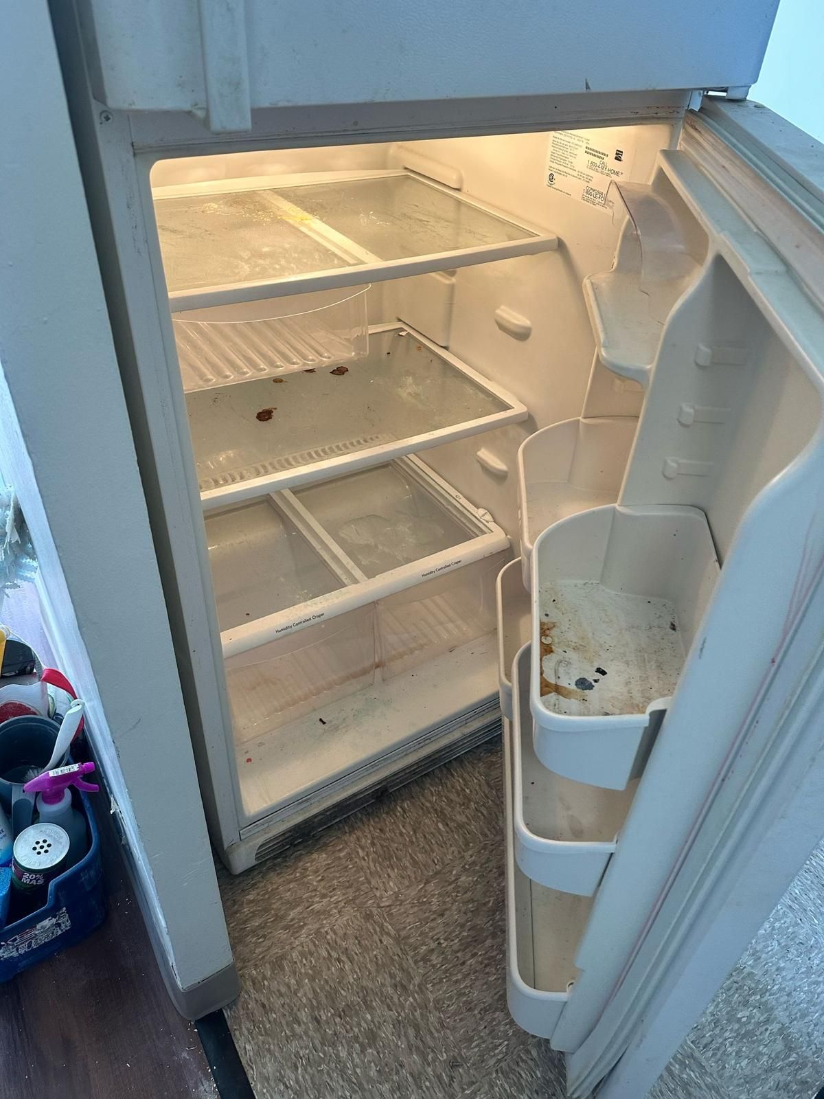 Open refrigerator interior, shelves and door compartments are visible. Dirty and empty.