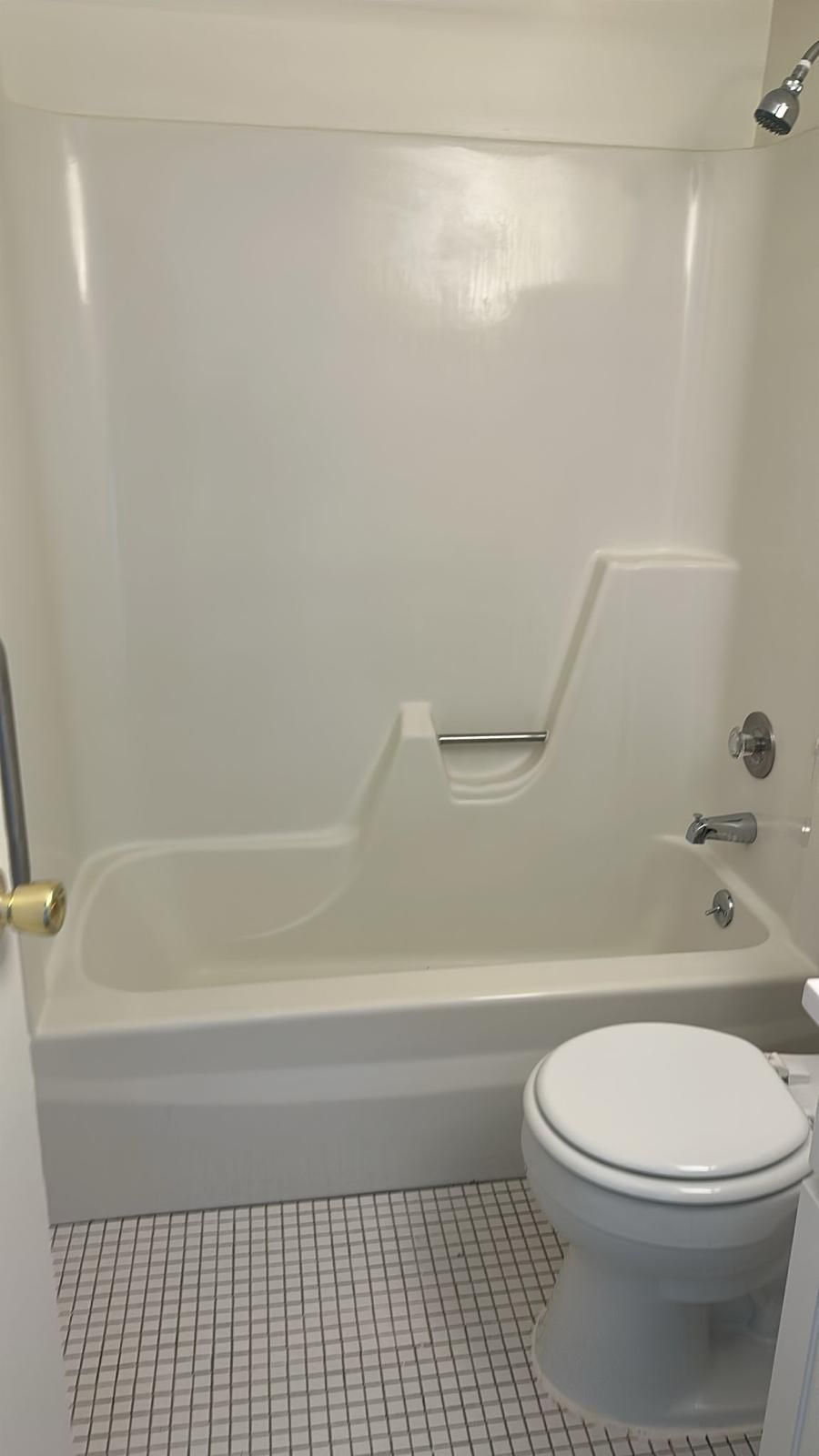 Bathroom with a white tub and shower combo, toilet, and tiled floor.