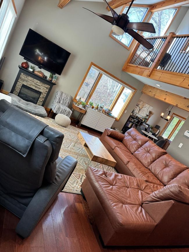 Living room with brown leather sectional, fireplace, and exposed beams.