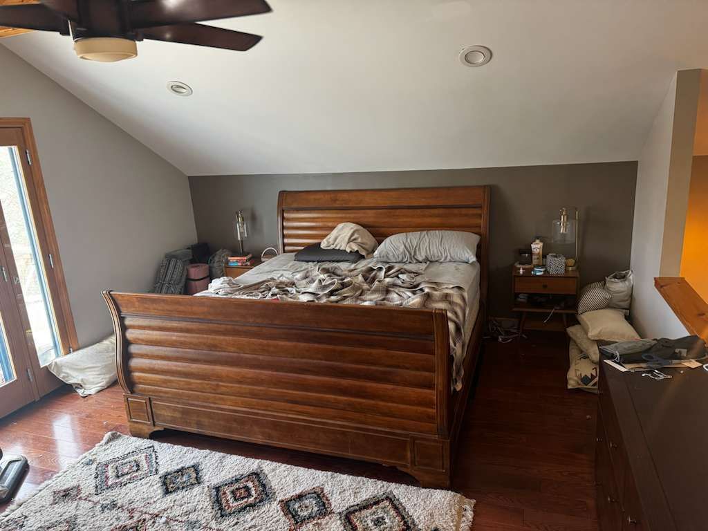 Bedroom with wooden bed, brown accent wall, and patterned rug.