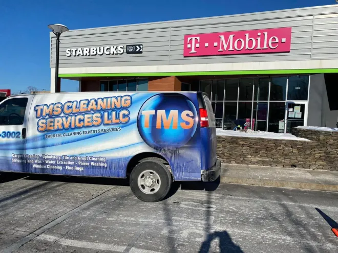 A TMS Cleaning Services van parked in front of a Starbucks and T-Mobile store.