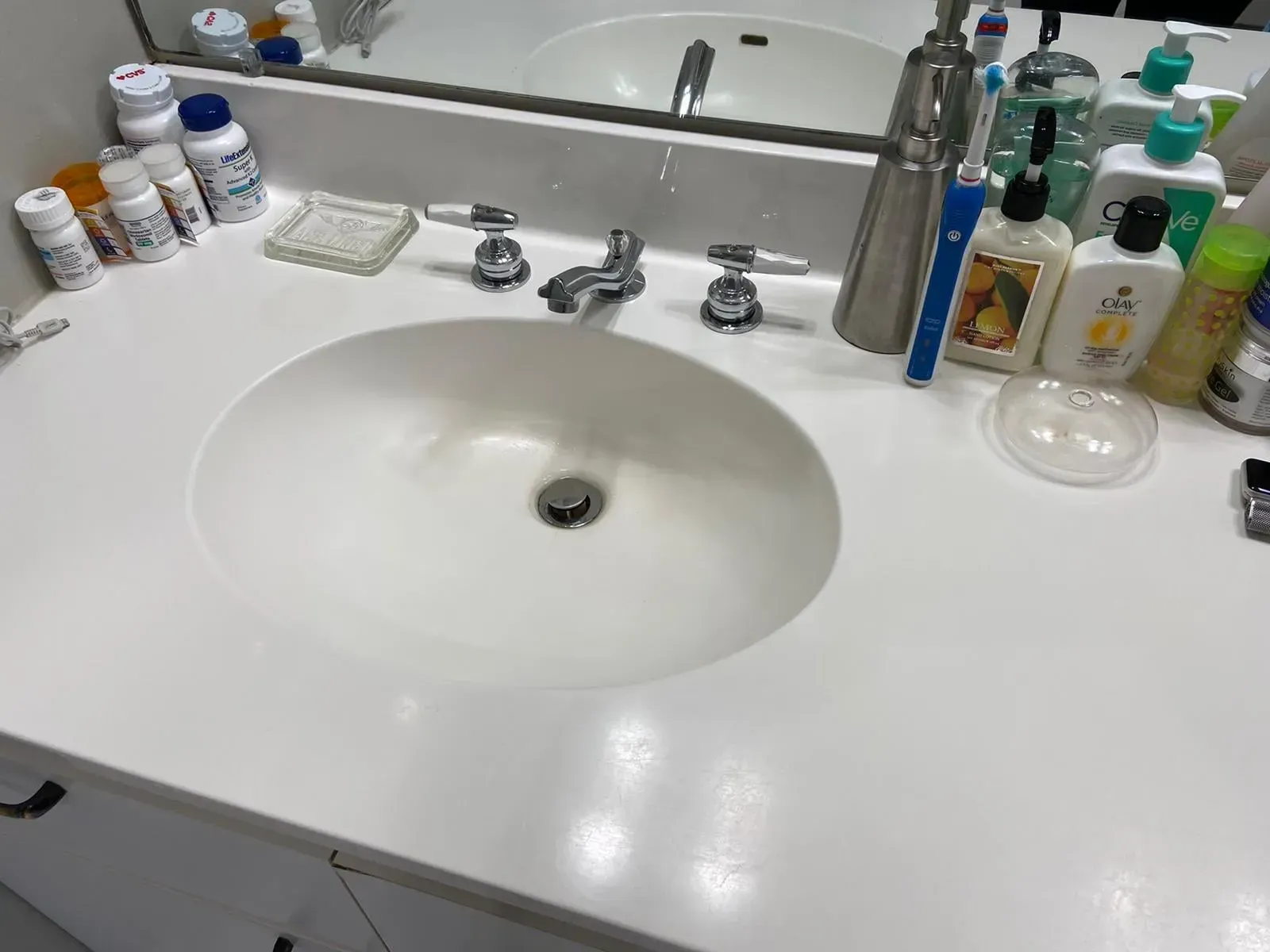 White bathroom sink with faucet and various toiletries on the counter.