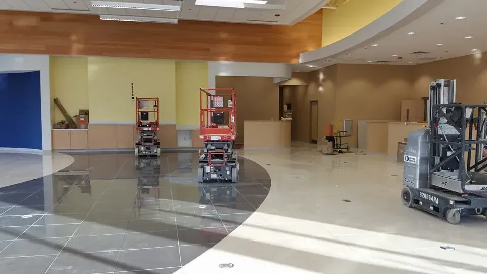Interior construction site: Two scissor lifts, unfinished walls, and a tiled floor.