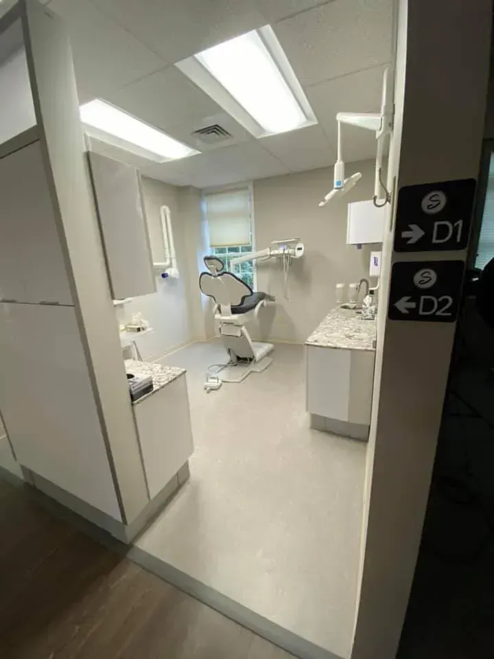 Dental office room with chair, equipment, and cabinets; signs for D1 and D2.