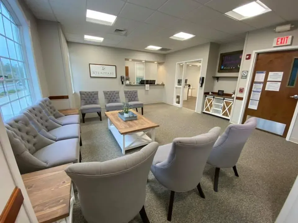 Waiting room with gray chairs, coffee table, and reception desk.