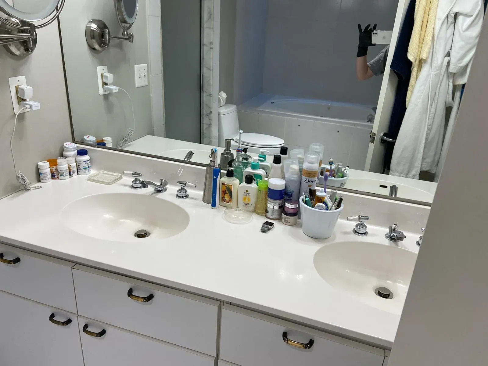Bathroom with double sinks, mirror, and various toiletries on the countertop.