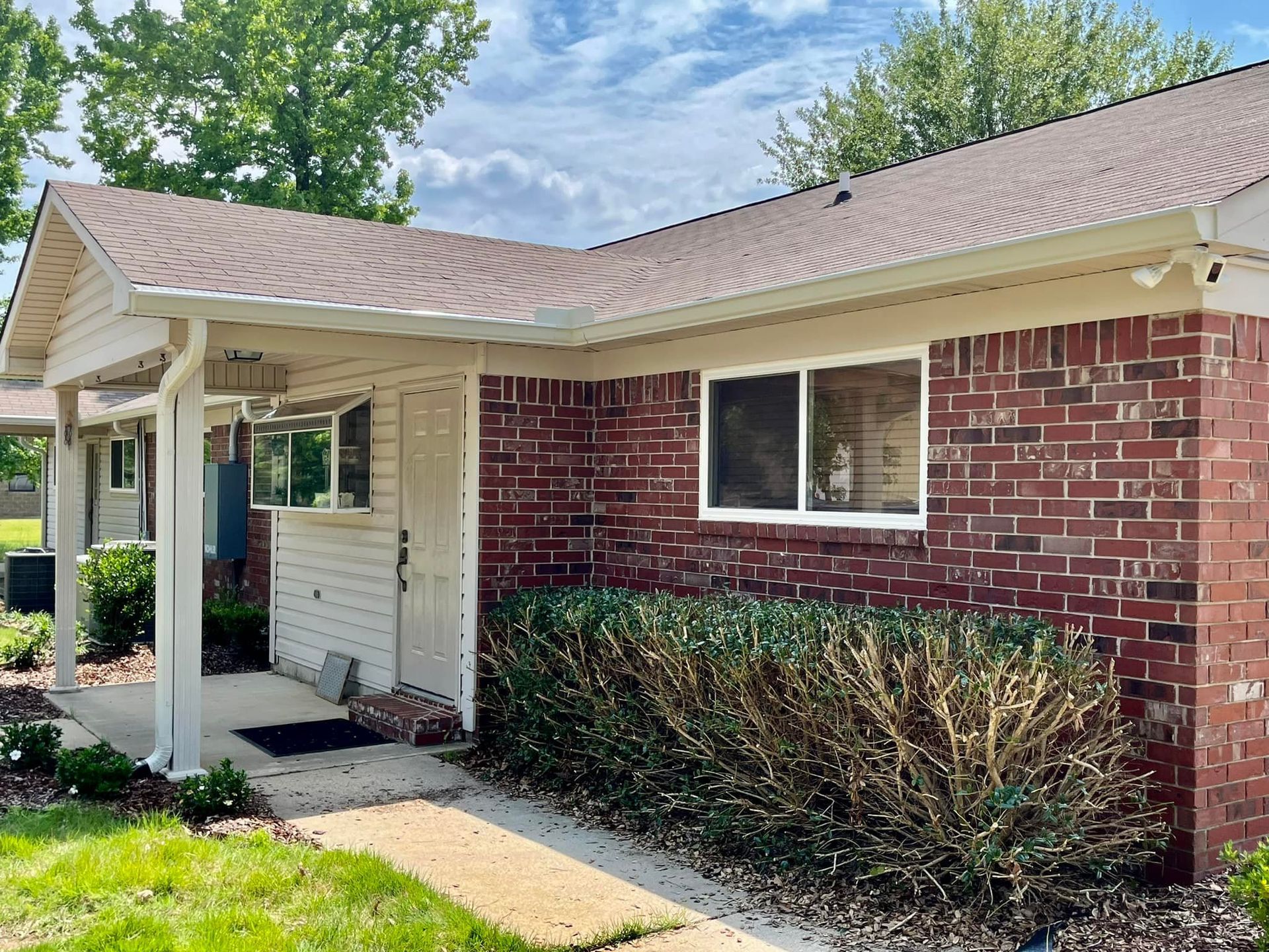 A small brick house with a porch and a white roof.