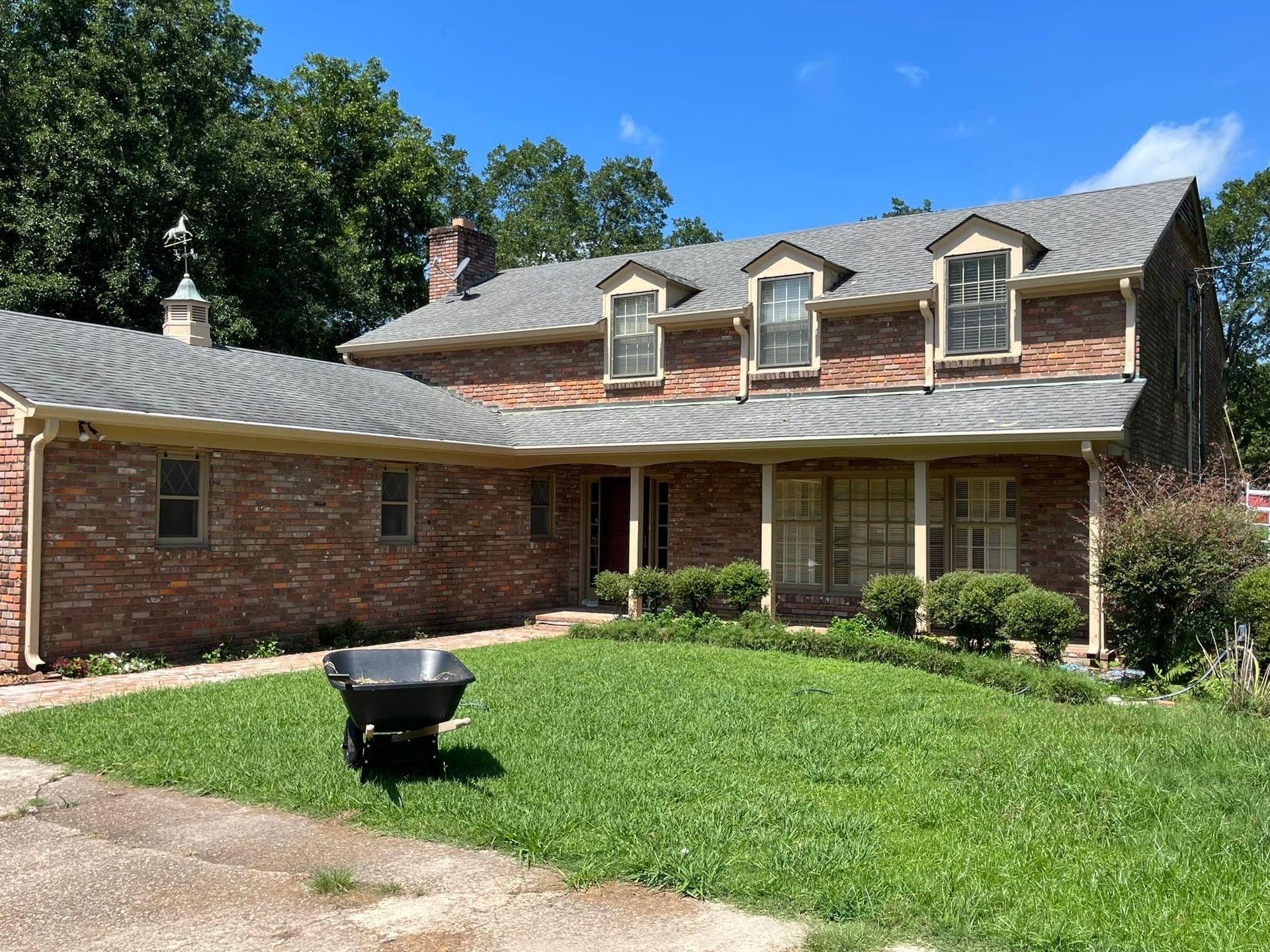 A large brick house with a wheelbarrow in front of it.