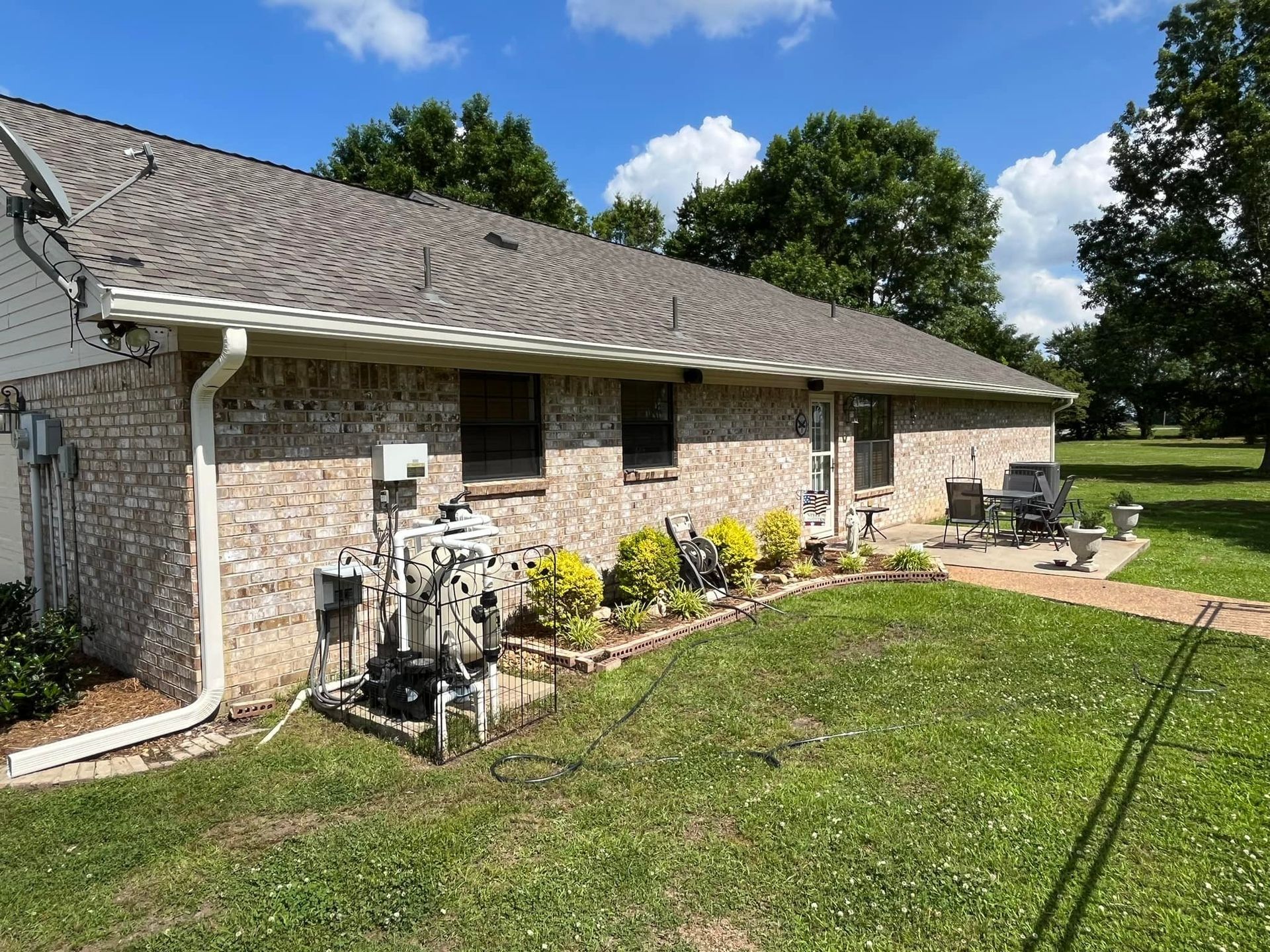 A brick house with a gray roof and a lawn in front of it.