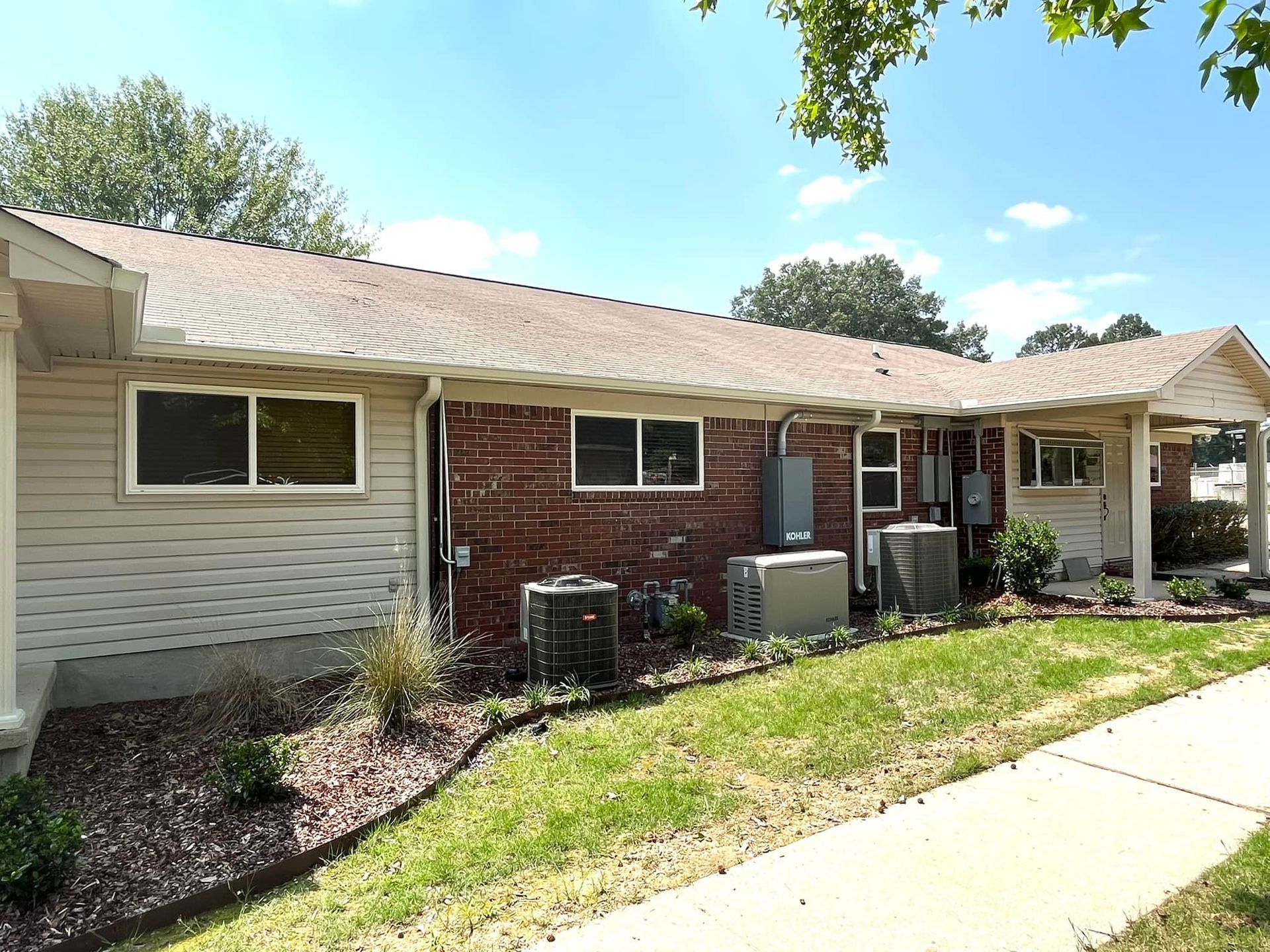 A brick house with a white siding and a brown roof