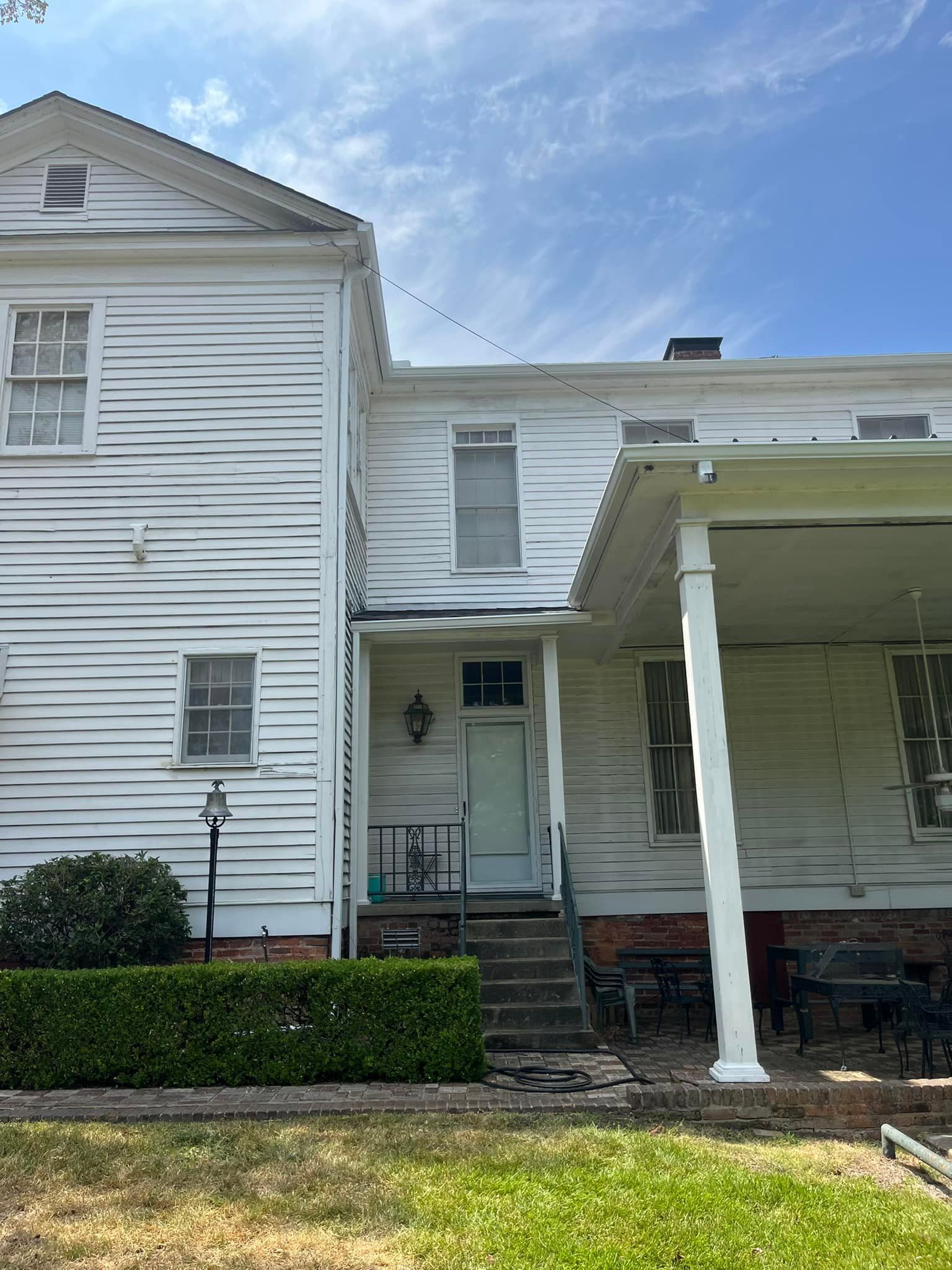 A white house with a porch and stairs in front of it.