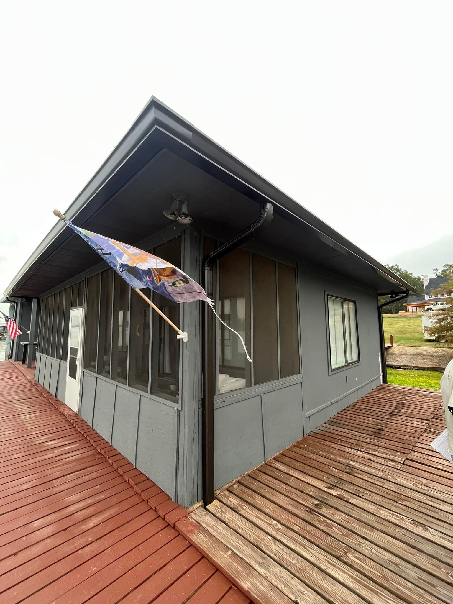 A small house with a screened in porch and a flag on the side.