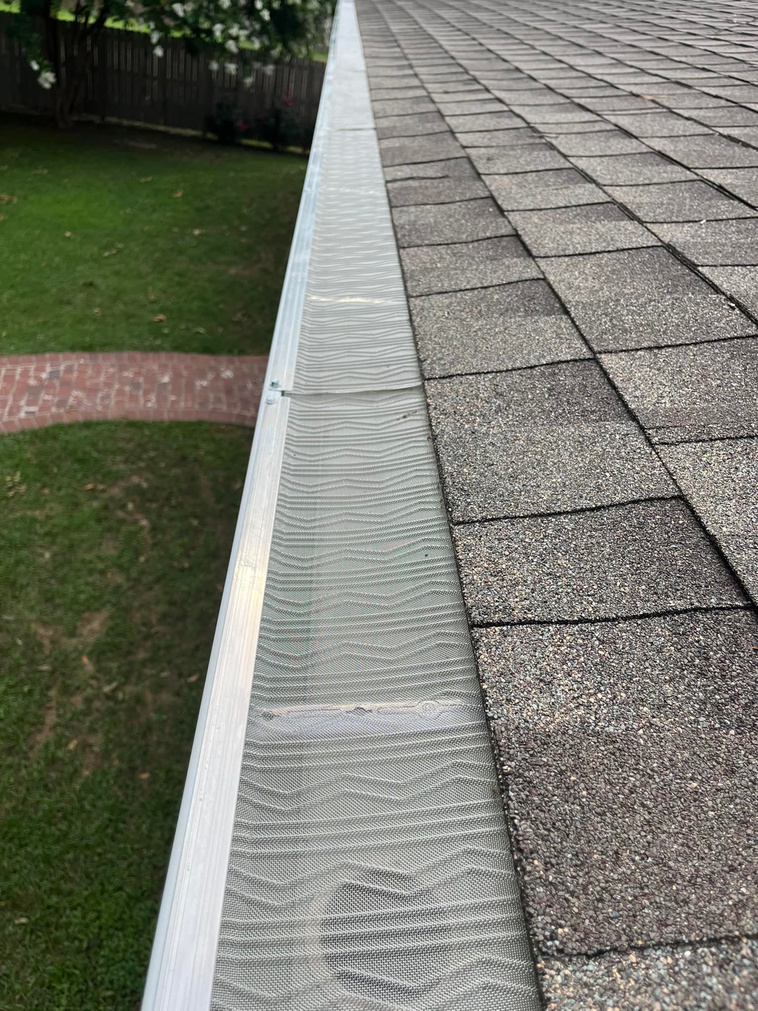 A close up of a gutter on a roof next to a lawn.