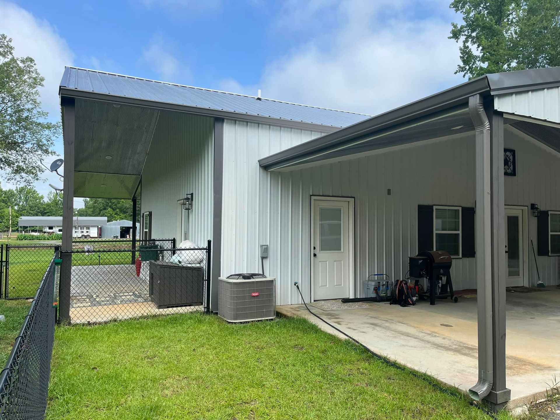A white house with a carport and a fence in front of it.