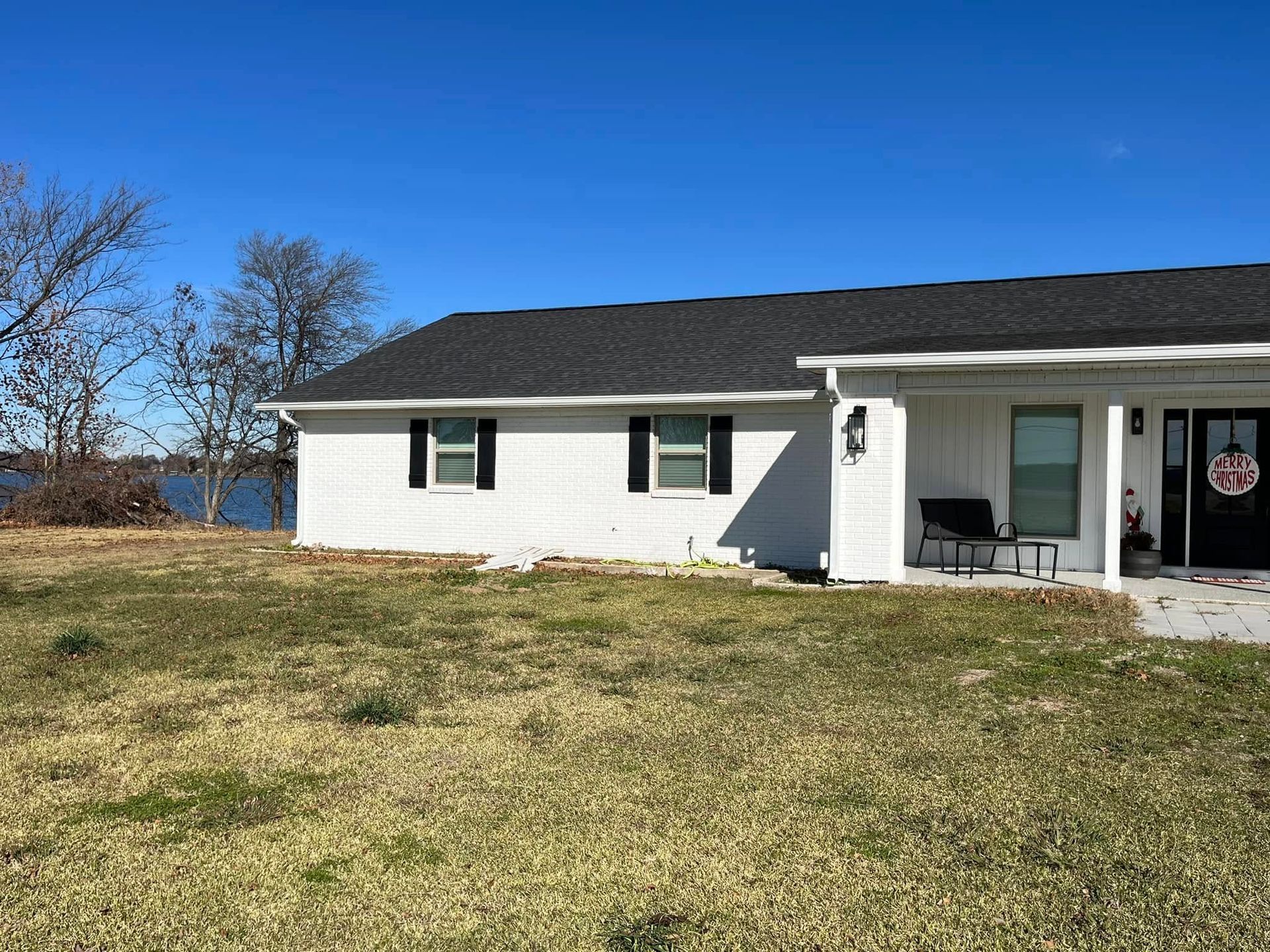 A white house with a black roof is sitting on top of a lush green field.