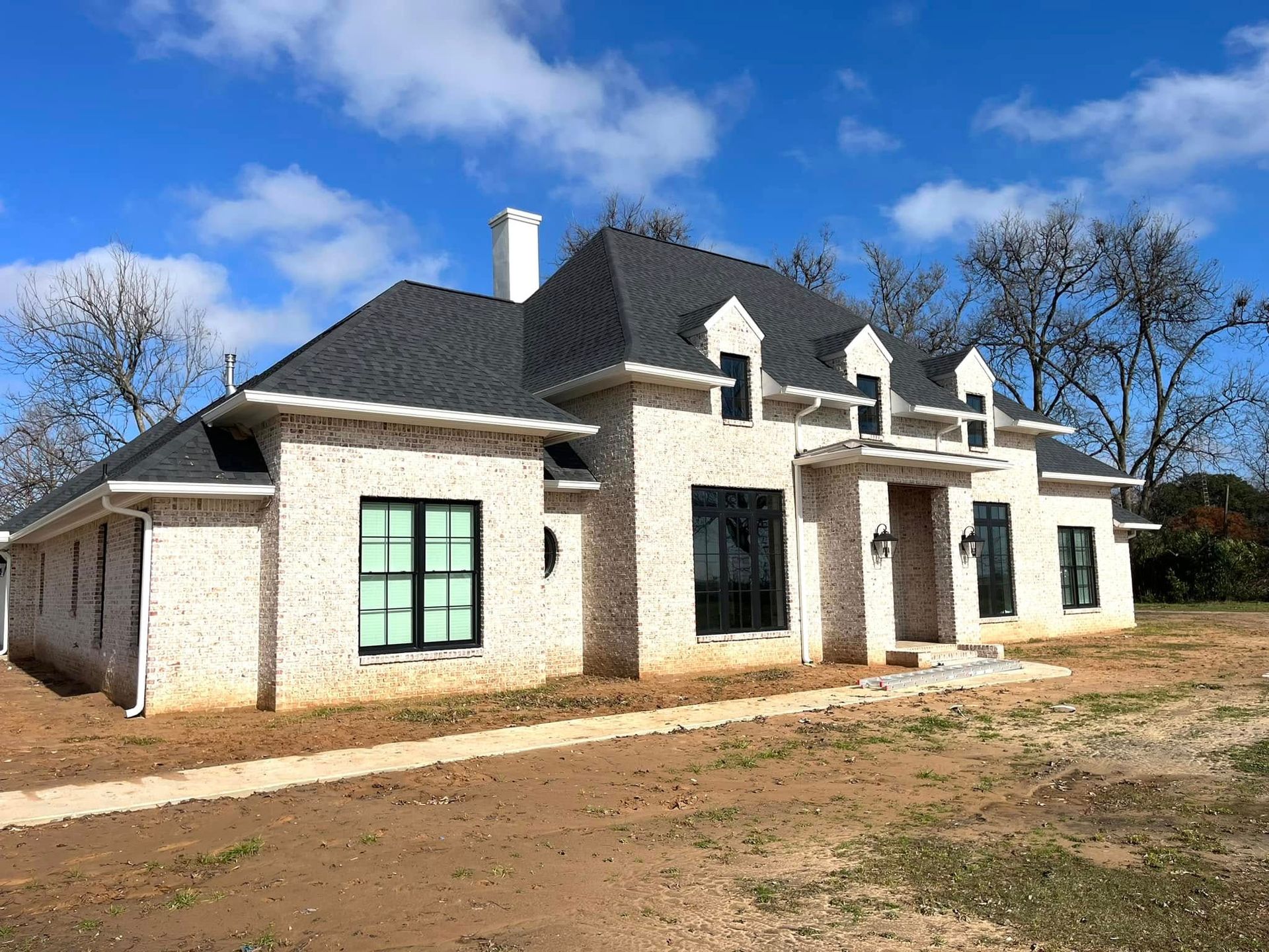 A large white brick house with a black roof