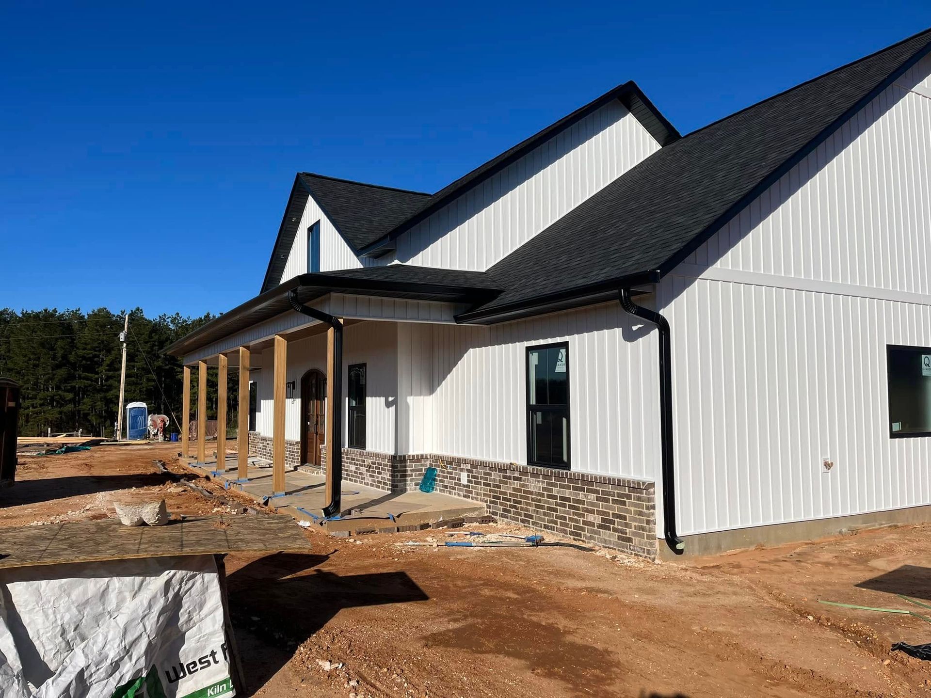 A large white house with a black roof is being built.